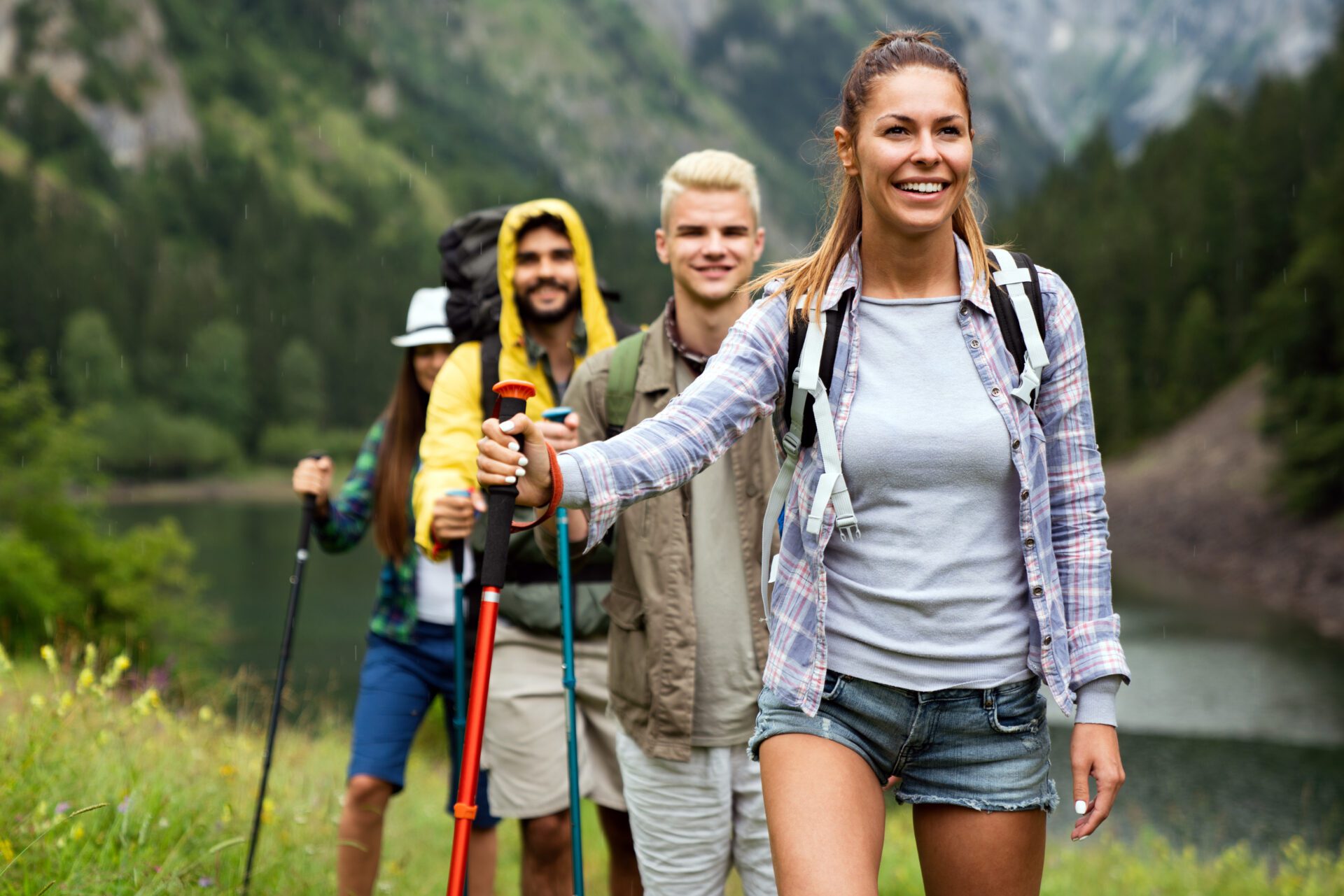 Group of smiling friends hiking with backpacks outdoors. Travel, tourism, hike and people concept. A beautiful house near by forest area