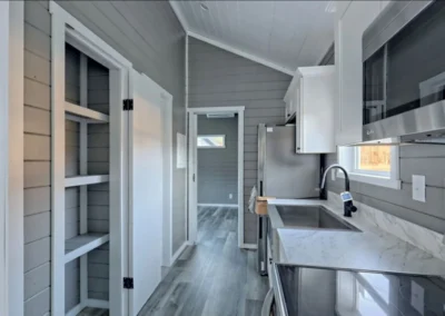 Partial view of a Savanna model home kitchen equipped with white cabinets and stainless steel appliances and a quartz countertop.